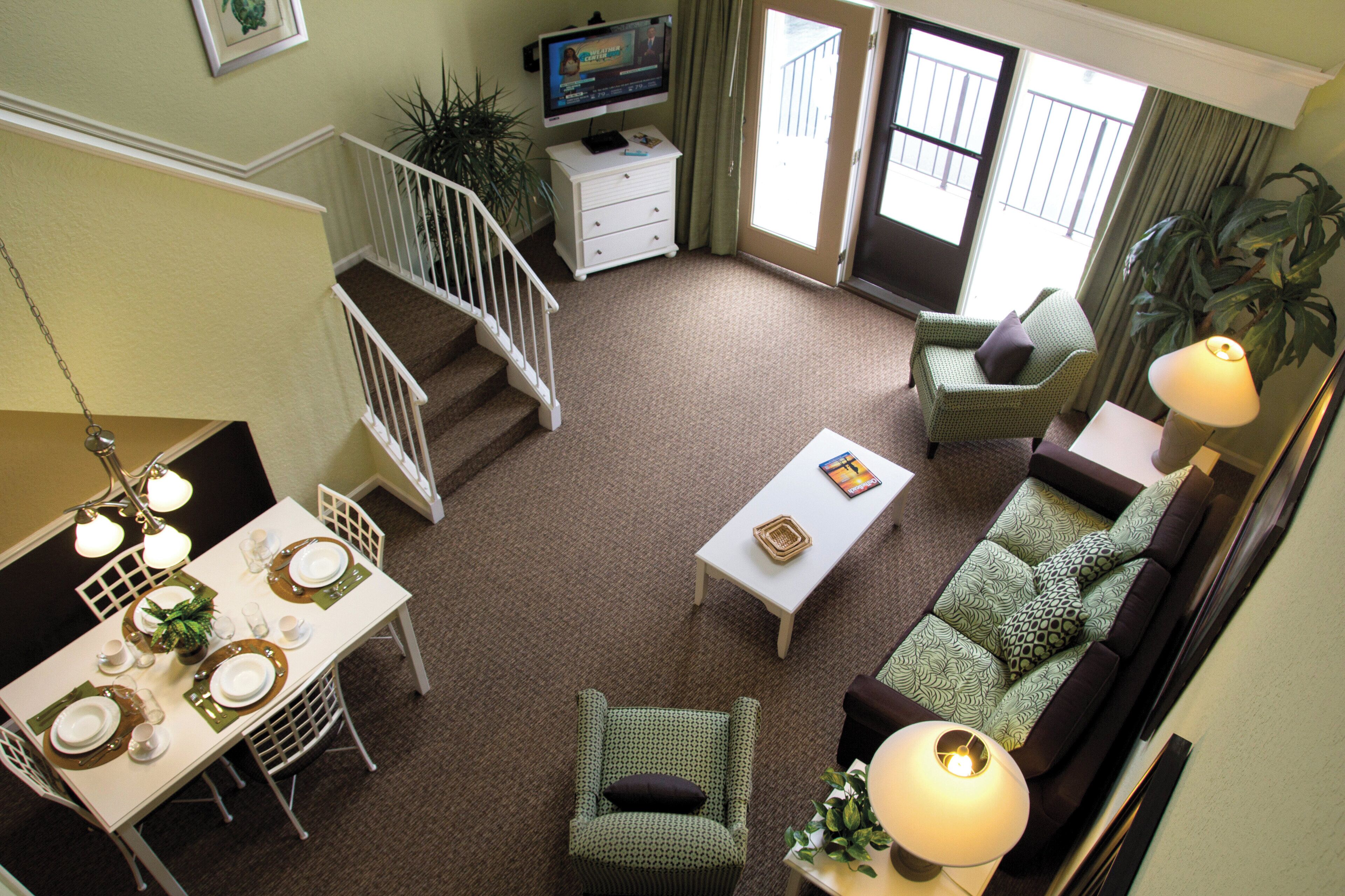 A spacious living room with a dining area, a staircase, and a television.