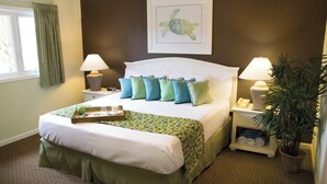 A neatly made bed with a tray, pillows, and a blanket in a room with a brown wall, a window with curtains, and a framed picture of a turtle. - Club Wyndham Grand Palms (Surfside Beach)