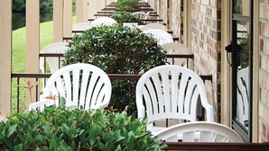 A covered outdoor seating area with rows of white chairs and tables, brick walls, and hanging light fixtures. - Club Wyndham Grand Palms (Surfside Beach)