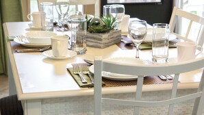 A dining table set with white plates, bowls, glasses, and cutlery. - Club Wyndham Grand Palms (Surfside Beach)