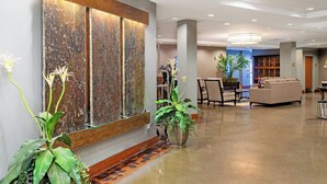 A hotel lobby with a large wooden wall feature, a reception desk, seating area, and a potted plant. - WorldMark Blaine (Blaine)