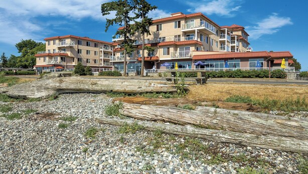 Ein mehrstöckiges Hotel mit Balkonen, einem Restaurant und Blick auf den Strand.