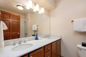 Un baño con dos lavamanos, un espejo, ducha y retrete.