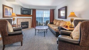 A hotel room with a sofa, two armchairs, a fireplace, a television, and a view of the sea through large windows. - WorldMark Blaine (Blaine)