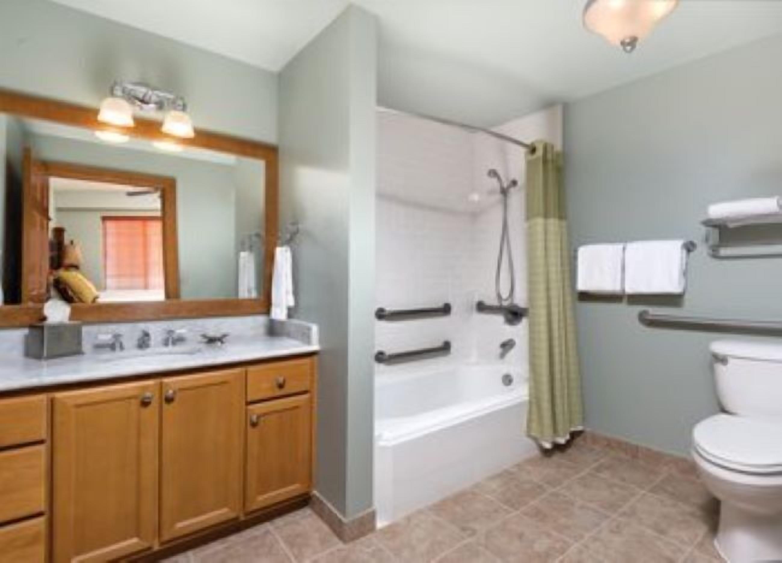 Un baño con tocador de madera, bañera, inodoro y ducha.