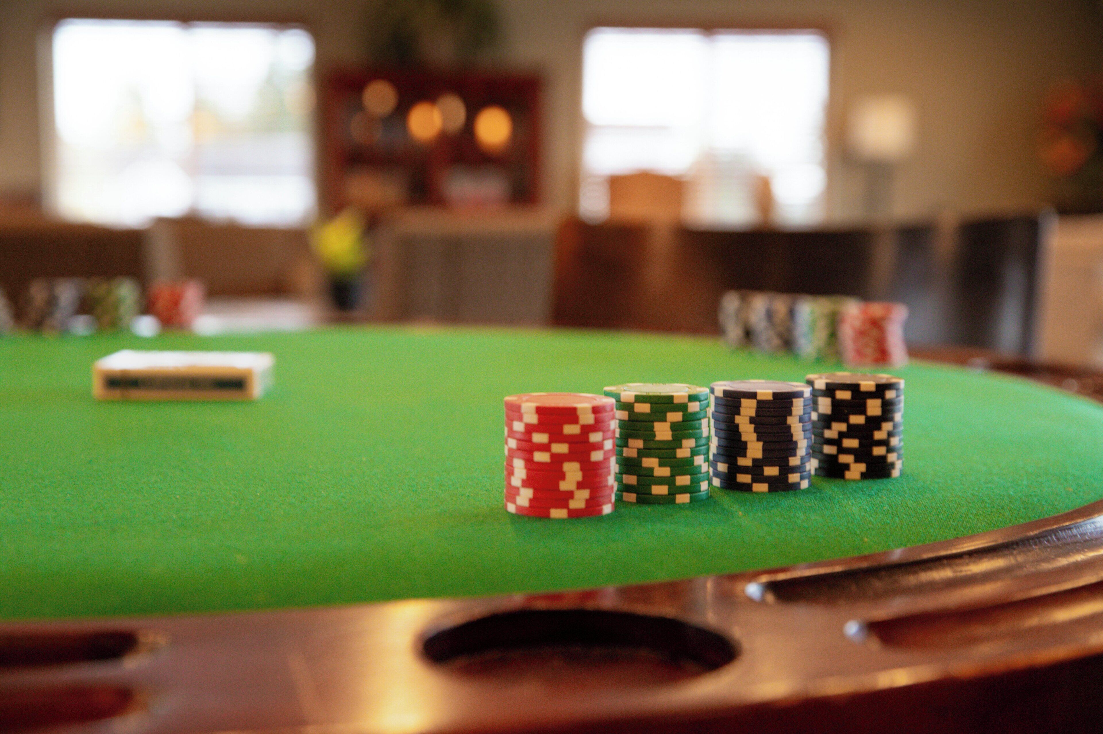 Une table recouverte d’un drap de feutre vert, avec des jetons de poker et un objet blanc posé dessus.