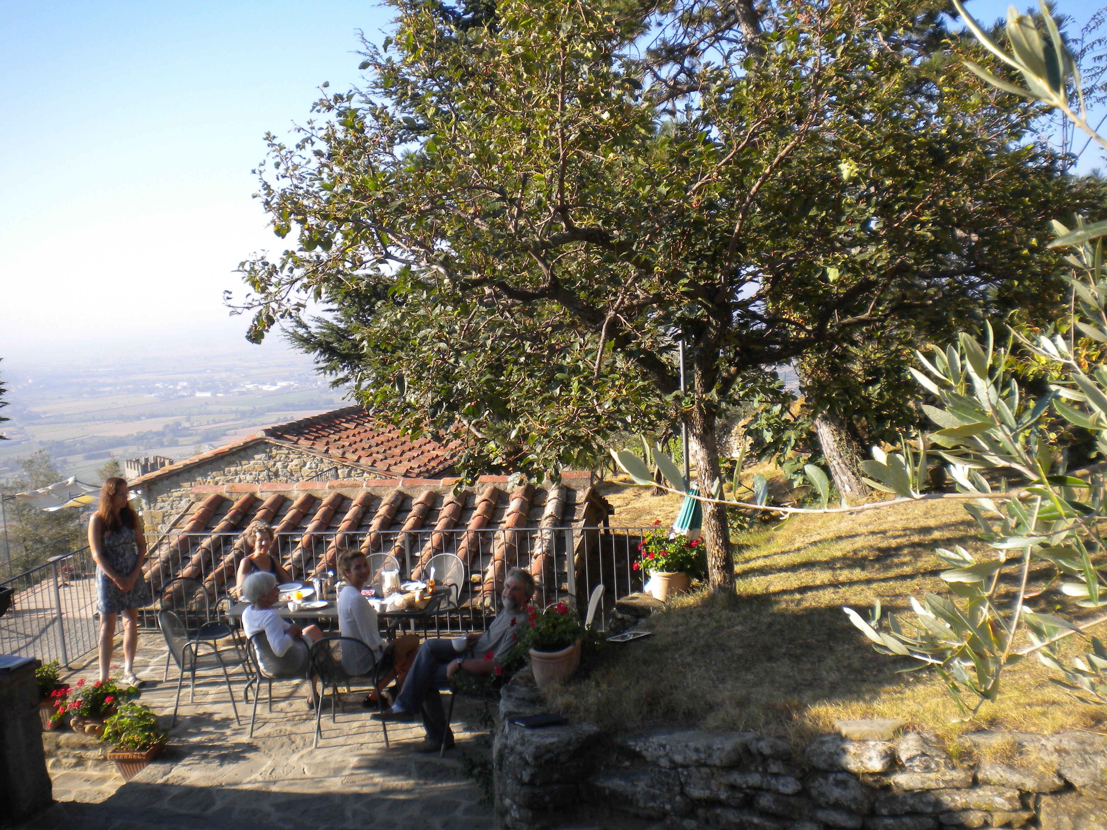 Una terrassa amb paviment de pedra, seients a l'aire lliure i plantes en testos.