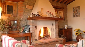 Un salón acogedor con chimenea de piedra, vigas de madera y mobiliario tapizado a rayas.