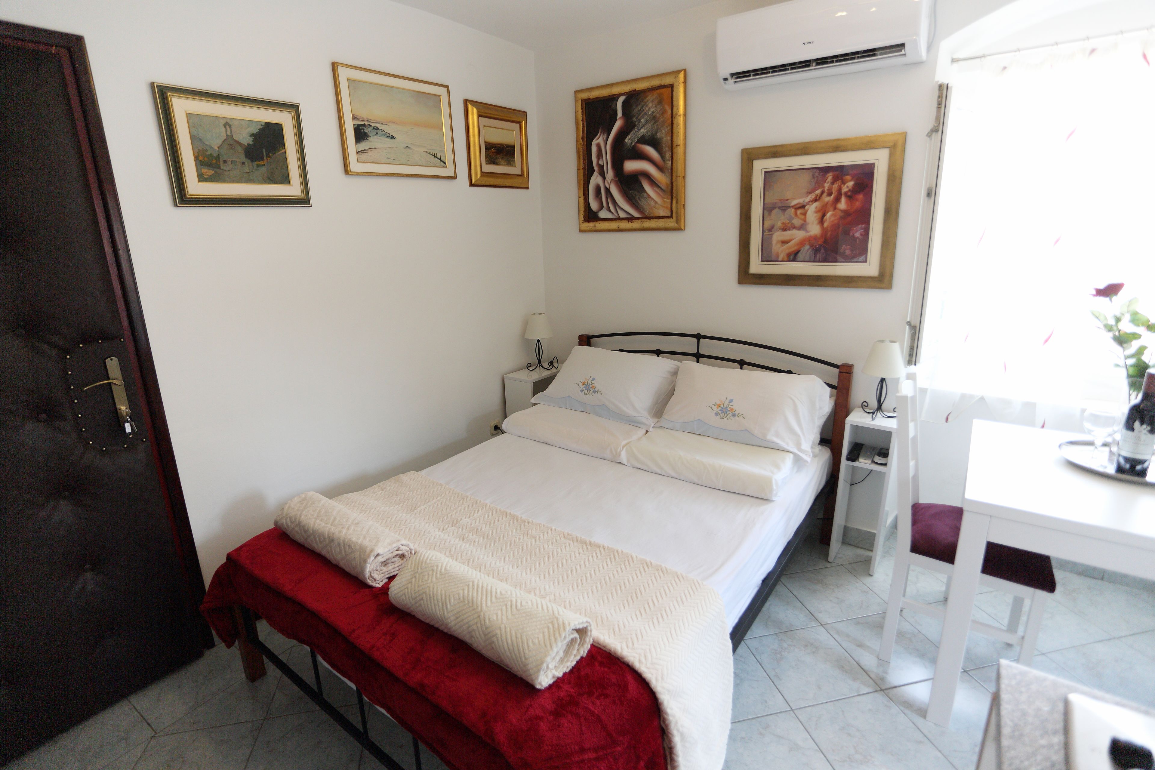A neatly arranged bedroom with a bed, bedside table, and a small desk with a chair.