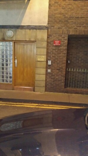 Un edificio de ladrillo con una puerta de madera y un cartel de advertencia de circuito cerrado.