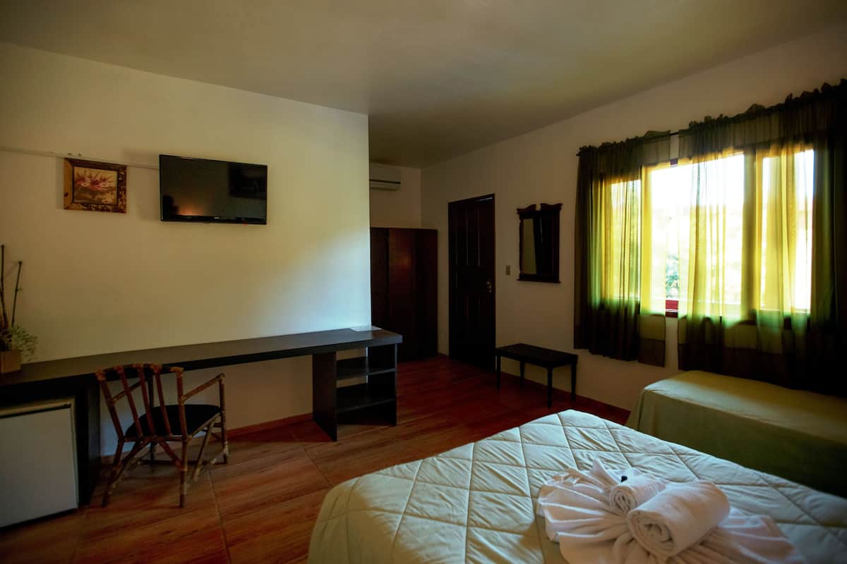 A hotel room with a bed, a desk, a chair, a television, and a window with curtains.