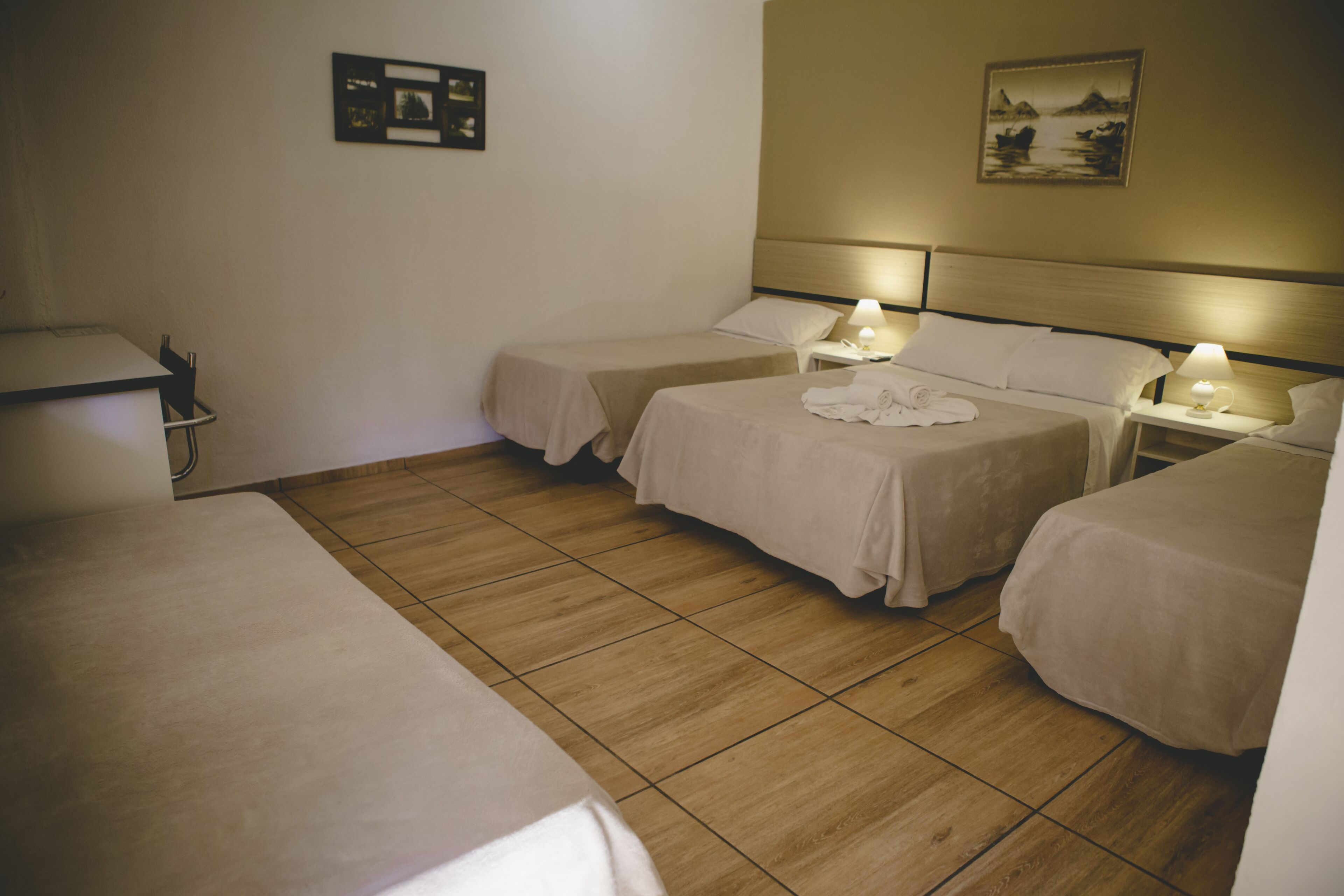 Een hotelkamer met twee eenpersoonsbedden, een bureau en een stoel. Er zijn wandlampen en een ingelijst kunstwerk aan de muur.