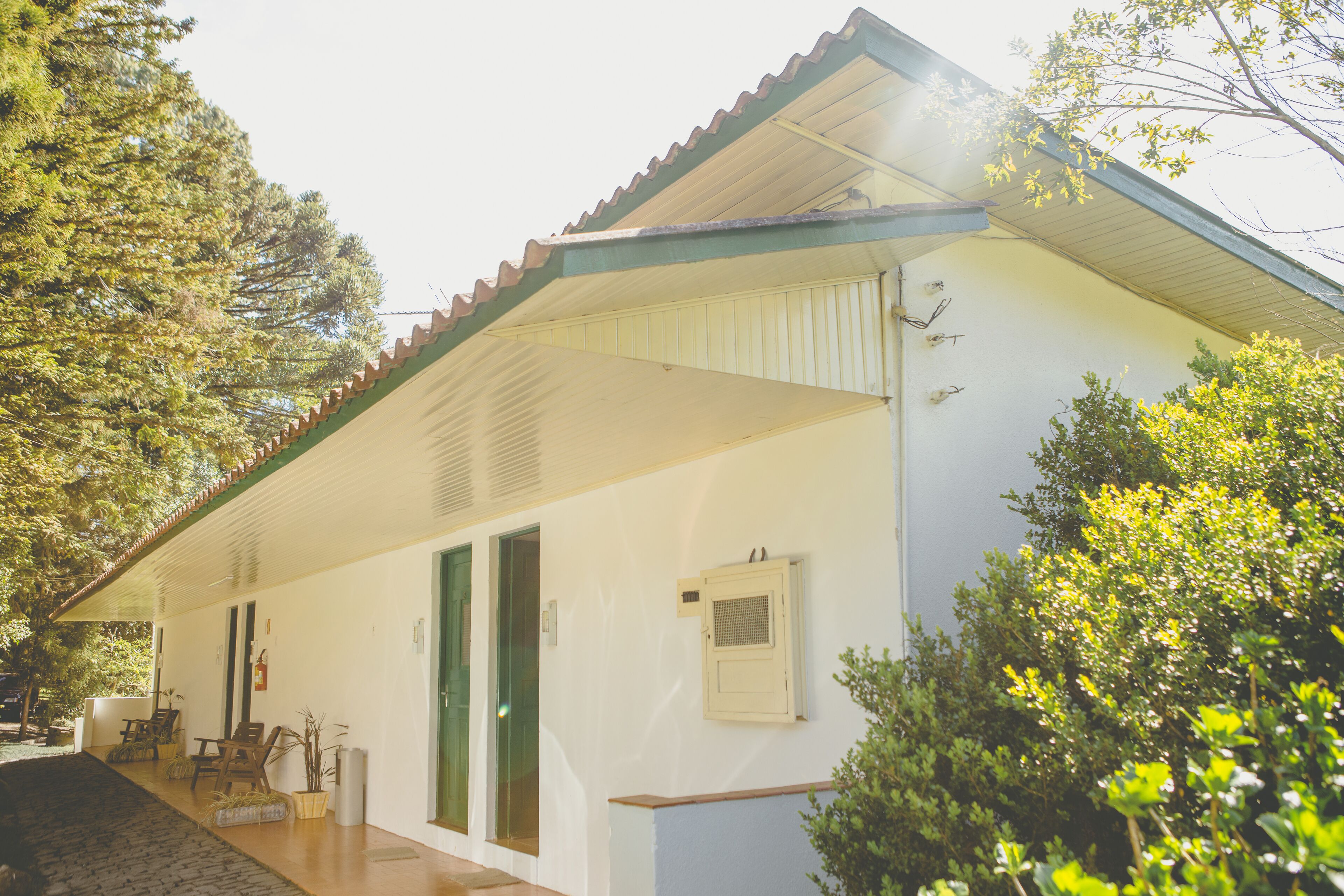 Un bâtiment blanc avec un toit recouvert de tuiles, un porche et une porte verte.