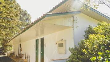 Un bâtiment blanc avec un toit recouvert de tuiles, un porche et une porte verte.
