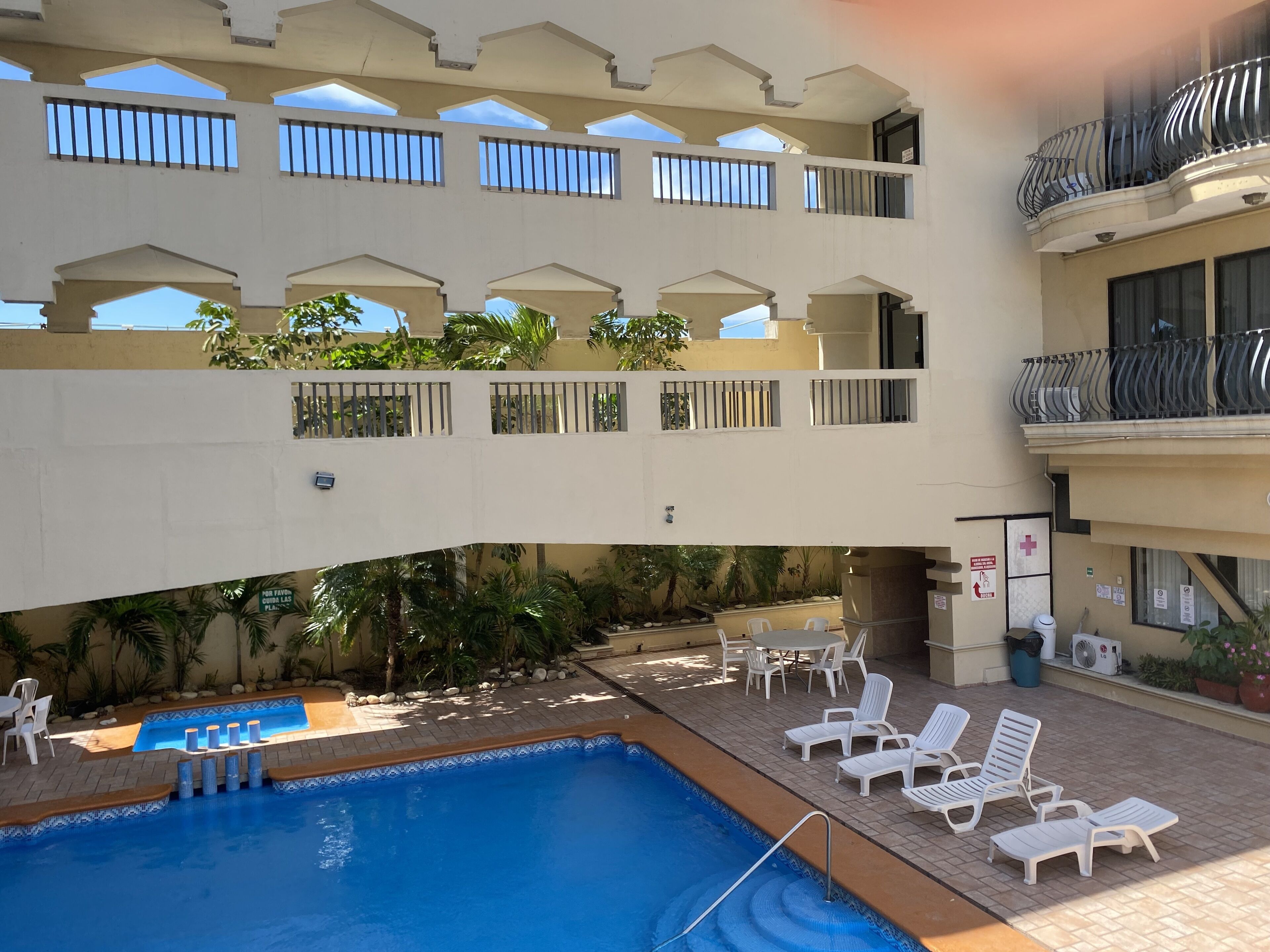 Un hôtel à plusieurs étages doté d’une piscine, d’un espace extérieur aménagé et de balcons.