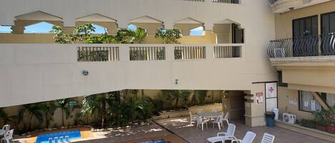 A multi-level hotel with a swimming pool, outdoor seating, and balconies.