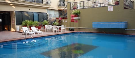 Una piscina al aire libre, sillones reclinables de piscina