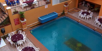 Un área de piscina interior con varias opciones de descanso y una piscina azul.