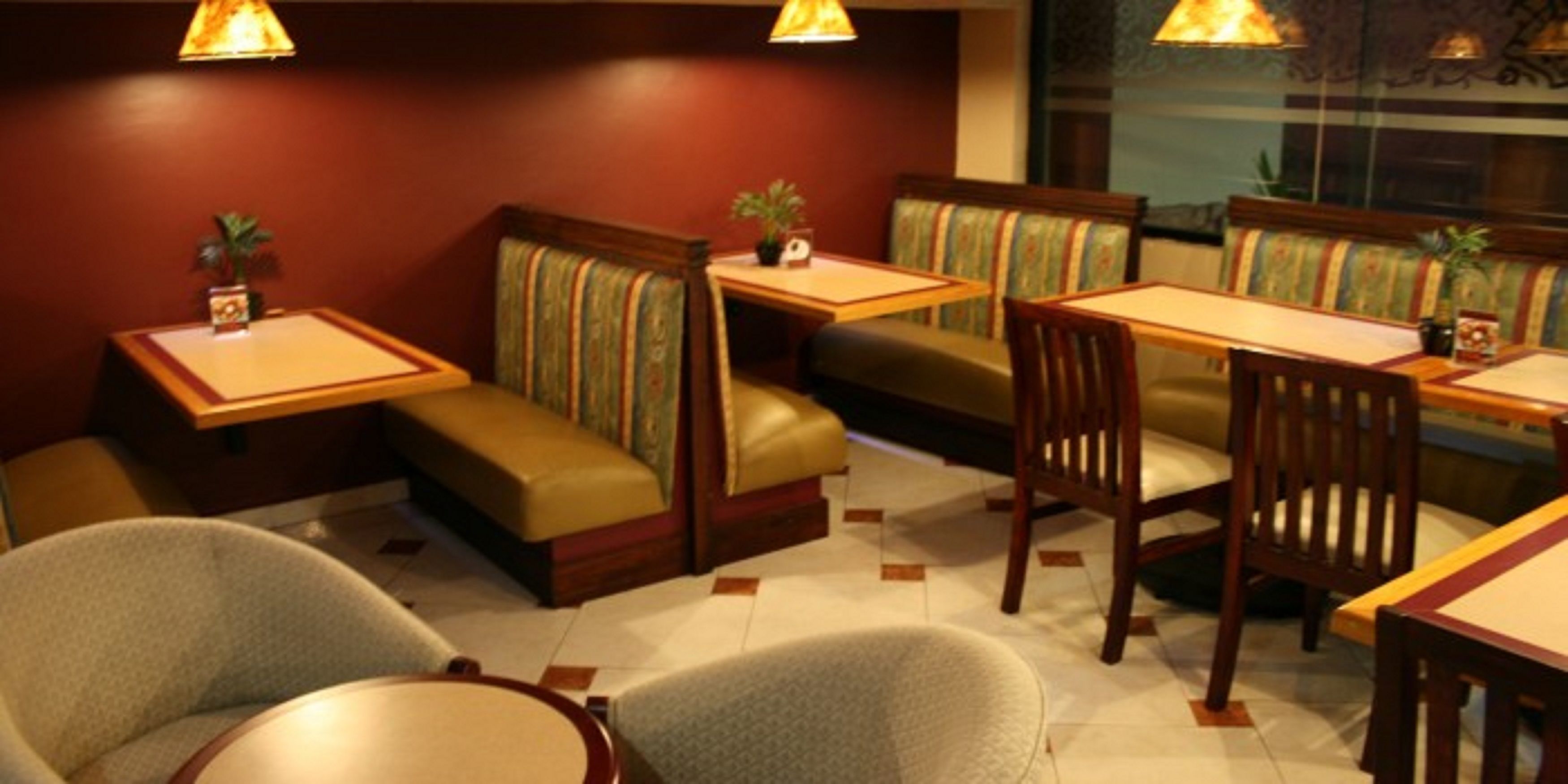 A restaurant with booths and tables, featuring cushioned seating and small side tables.
