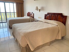 Duas camas de casal com cabeceiras de madeira, um telefone e uma luminária na parede em um quarto de hotel com uma janela grande e vista para o exterior.