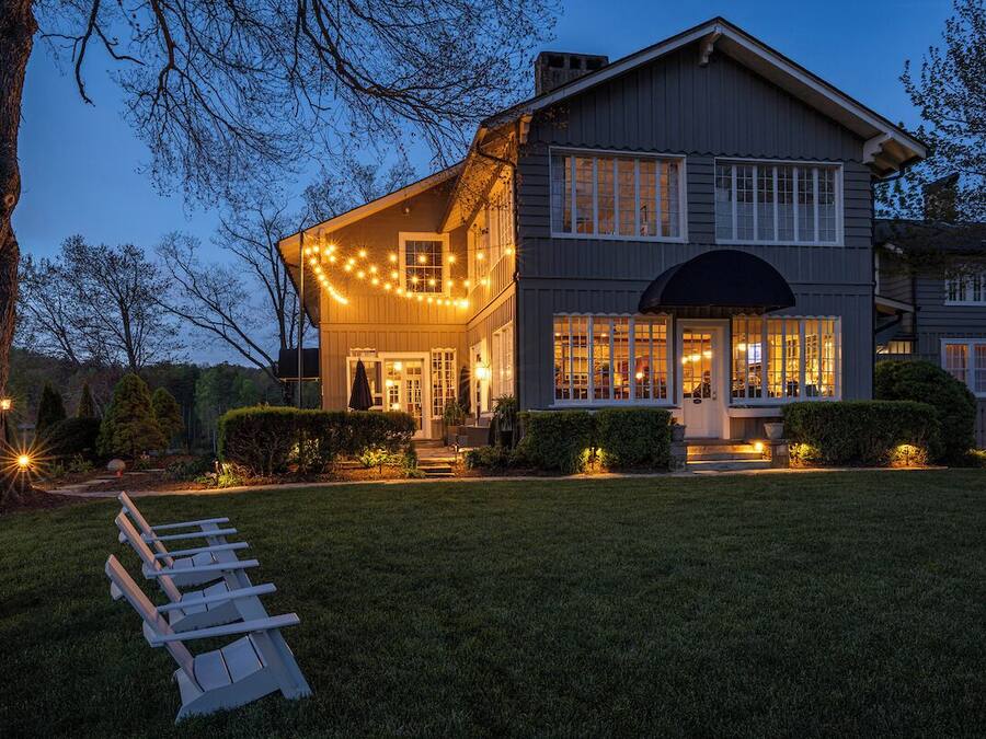 Una casa de dues plantes amb un porxo cobert i llums lluminoses.