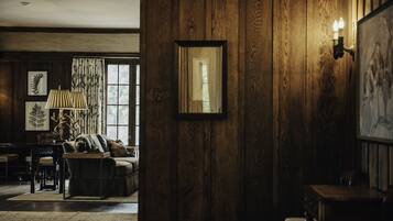 Una habitación con paneles de madera, un espejo enmarcado, una lámpara y un sofá con cojines.