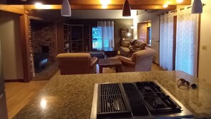 A kitchen with a gas stove and a dining area with a sofa and table. - In town home- above the 1880 train.  Walk to Main St!— recently updated! (Hill City)