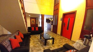 A lobby with a black sofa set, a coffee table, and a red door. - Casona Quera (Cusco)