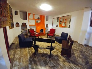 Un saló amb una llar de foc, diverses cadires i una banca.