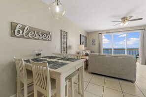 Relax in this inviting living area with a dining table for four, comfortable sofa, and ocean views through large windows.