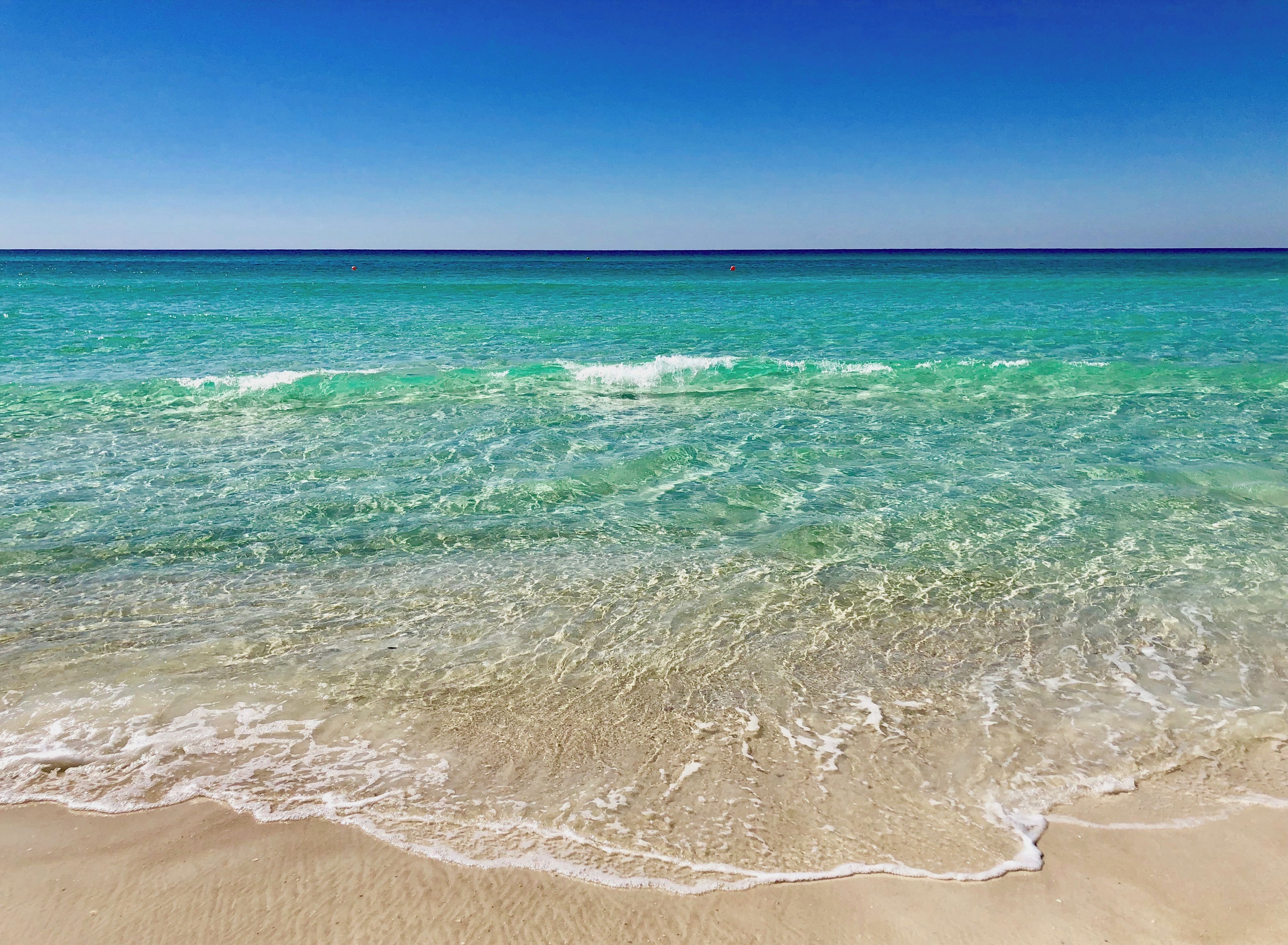 Une plage à l’eau turquoise et limpide, où les vagues sont douces.