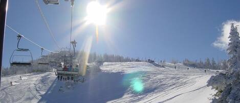 A ski lift with cables and chairs, a clear sky, and a snowy landscape.