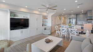 A modern living room with a flat-screen TV, white furniture, and a ceiling fan. - Splash in the water, play in the sand, REJUVENATE! 205- Destin Seafarer (Destin)