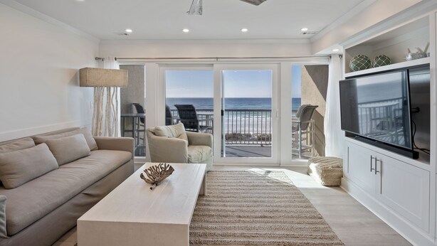 A spacious living room with a large window, a ceiling fan, a flat-screen TV, and a cozy seating area. - Splash in the water, play in the sand, REJUVENATE! 205- Destin Seafarer (Destin)