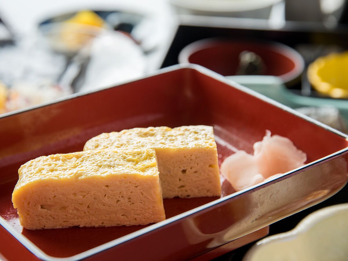 A rectangular red plate with two square pieces of food and a small amount of pinkish substance.