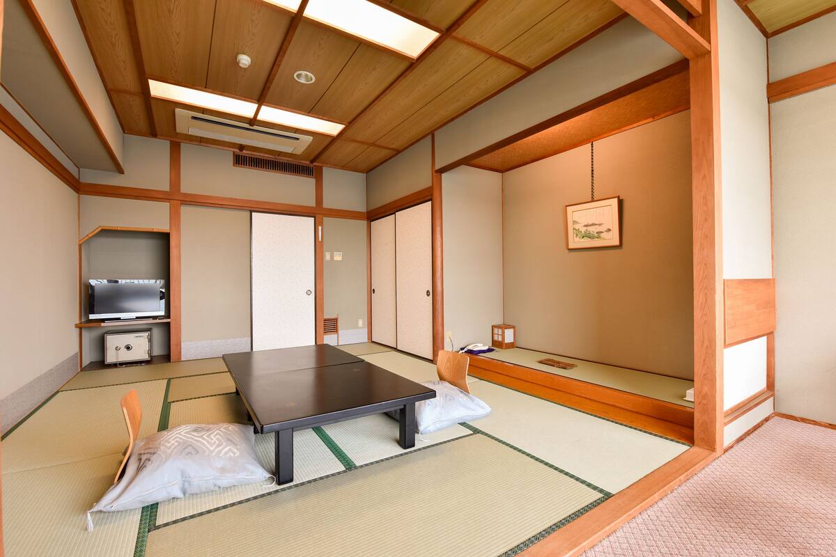 A traditional Japanese room with tatami flooring, a low table, a futon bed, and sliding doors.