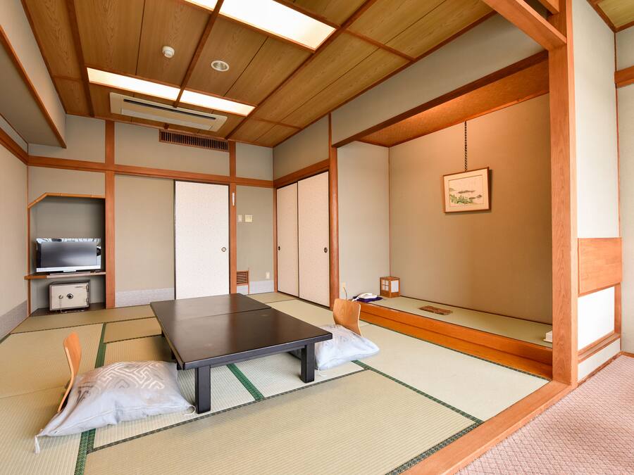 A traditional Japanese room with tatami flooring, a low table, a futon bed, and sliding doors.