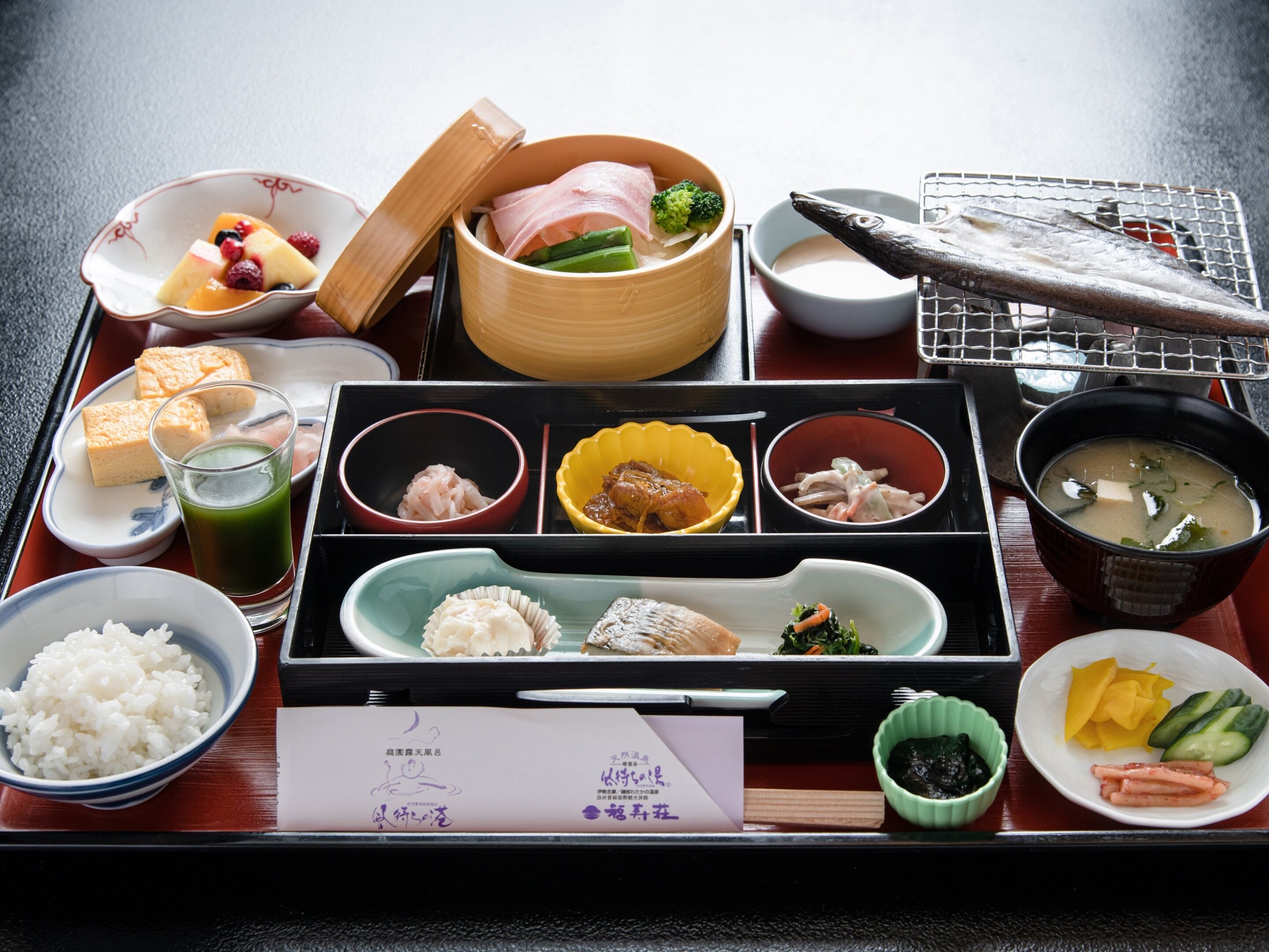A traditional Japanese meal set on a wooden table with various dishes including rice, fish, and vegetables.
