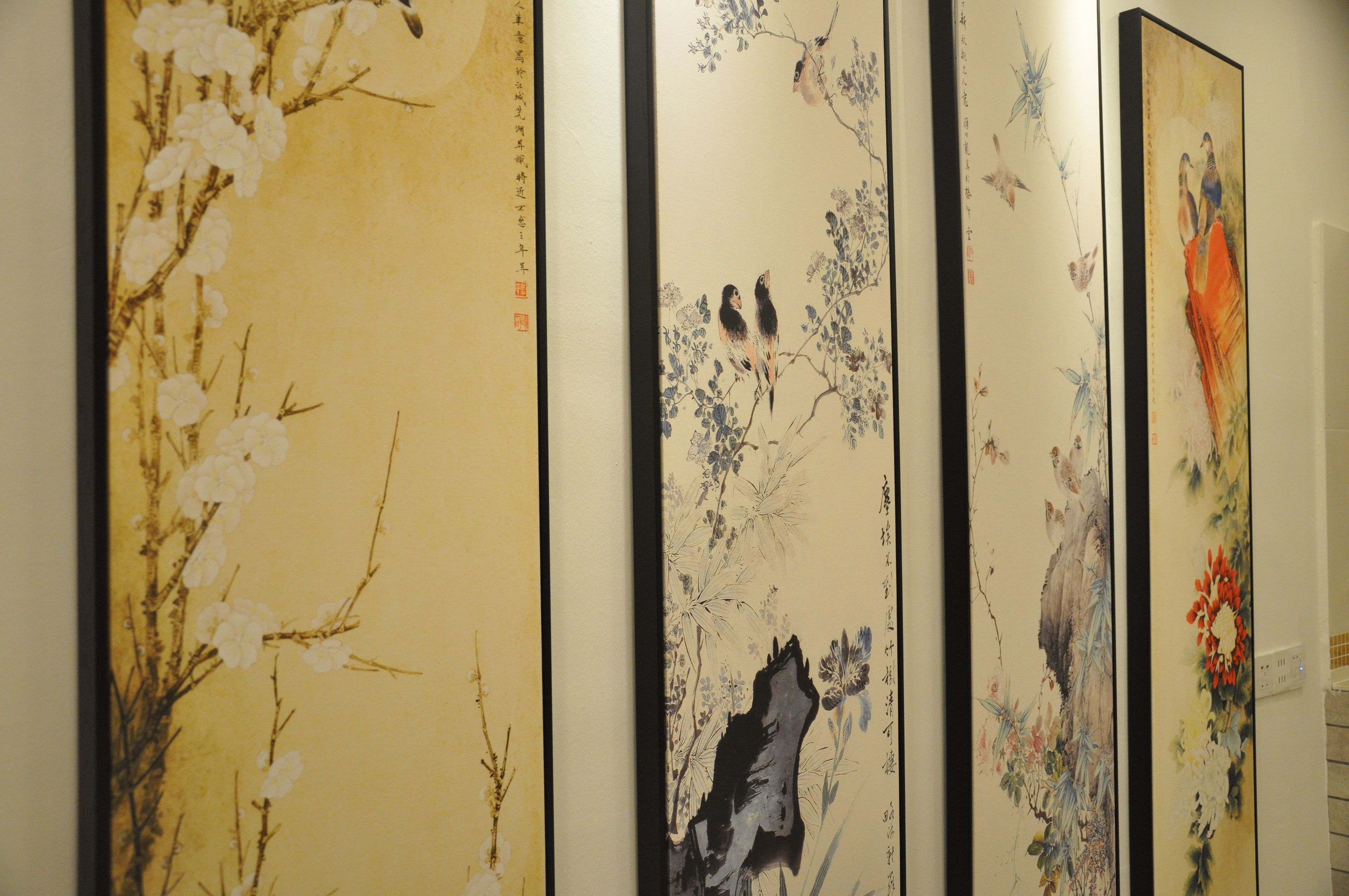 A series of traditional paintings on a wall, each depicting different floral and avian subjects.