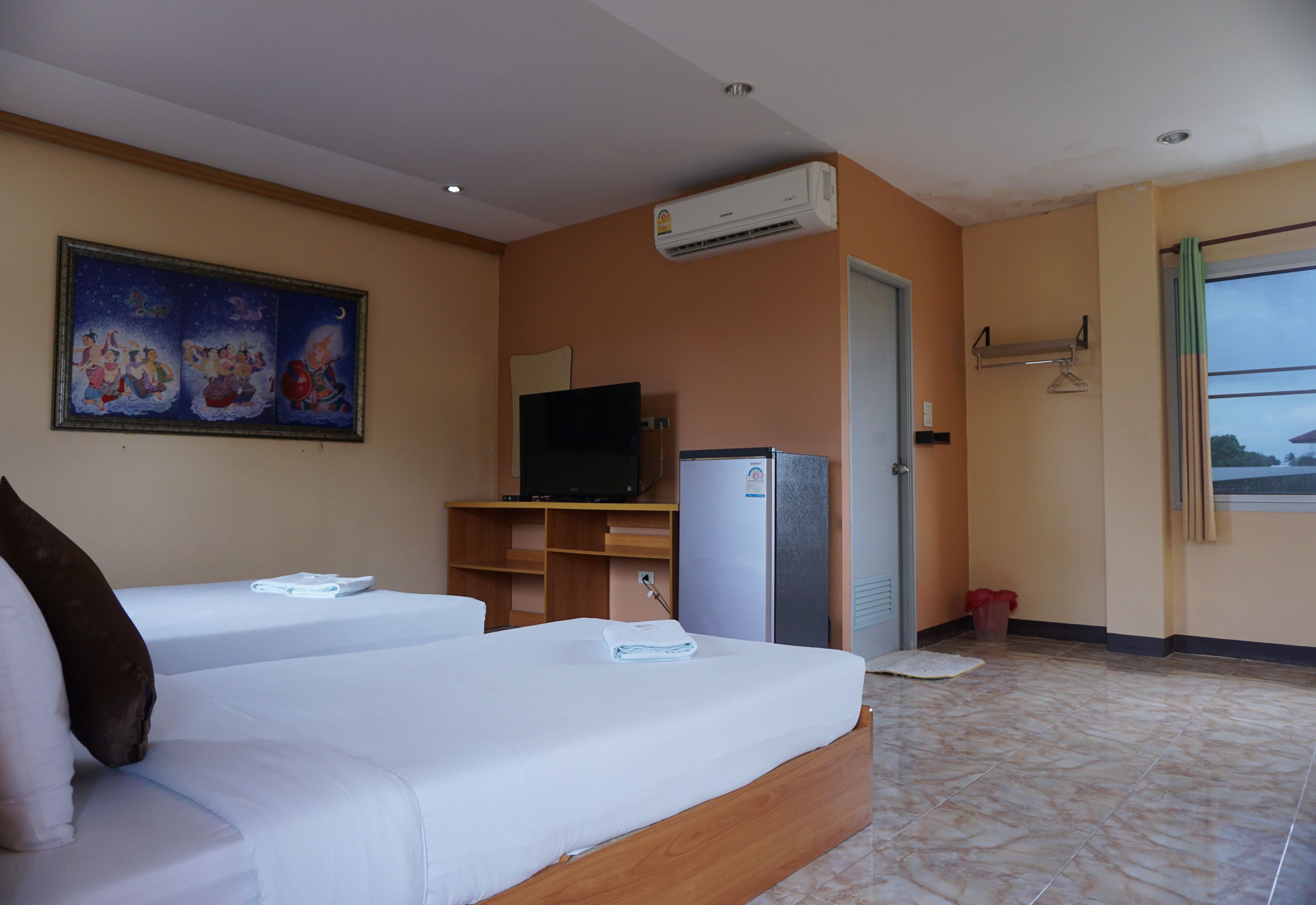 A hotel room with two beds, a TV, a refrigerator, and a painting on the wall.