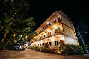 A multi-story hotel with balconies, a parking area, and potted plants. - Phoemphoon 2 Hotel (Nan)