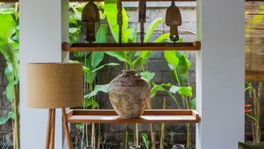 A room with a traditional design, featuring a bamboo ceiling, a white wall, and a shelf with multiple vases. - Atelier TE Designer Guesthouse (Denpasar)