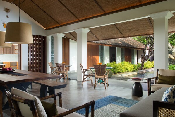 A spacious outdoor dining area with wooden furniture and a covered seating area. - Atelier TE Designer Guesthouse (Denpasar)