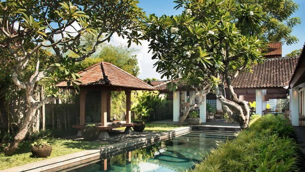 A serene pool area with a wooden gazebo, surrounded by lush greenery and traditional architecture. - Atelier TE Designer Guesthouse (Denpasar)