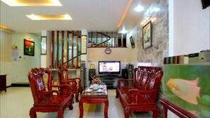 A traditional-style living room with wooden furniture, a television, and a fish tank. - Cosy House Homestay (Da Nang)