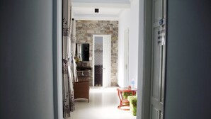 A hallway leading to a kitchen with a stone wall, a sink, and a small table with a water bottle. - Cosy House Homestay (Da Nang)