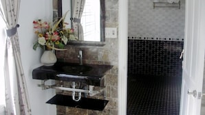A bathroom with a black sink, a mirror, and a vase of flowers. - Cosy House Homestay (Da Nang)