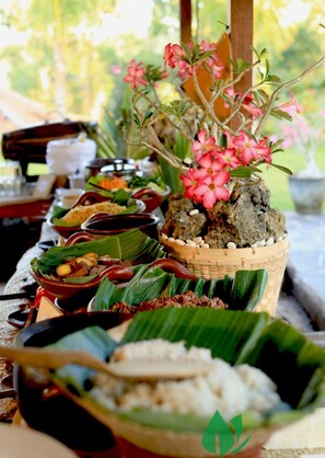 A variety of dishes served on banana leaves, arranged on a table outdoors.