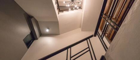 A staircase with a modern design, featuring a black metal railing and wooden steps.