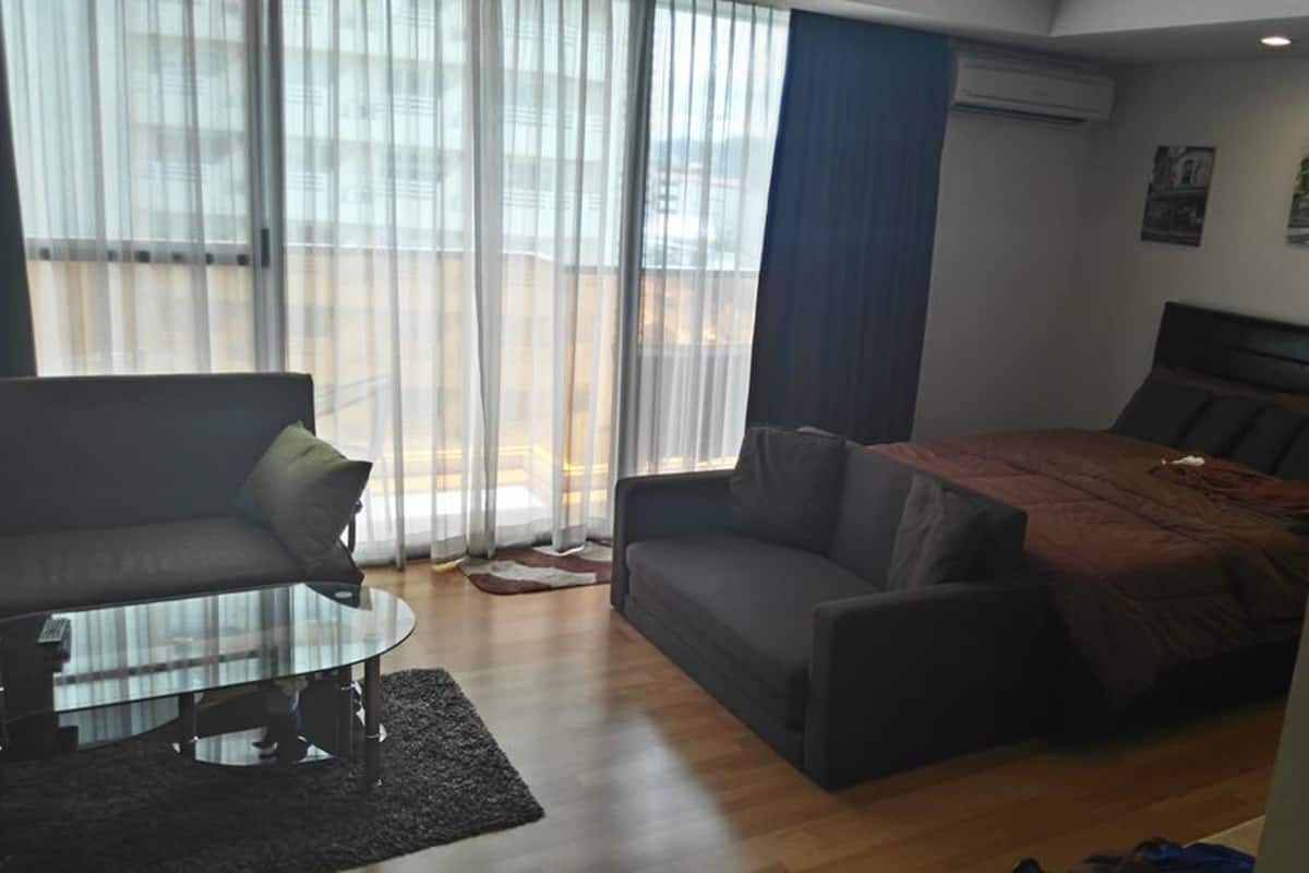 A modern hotel room with a large bed, a sofa, and a glass coffee table.